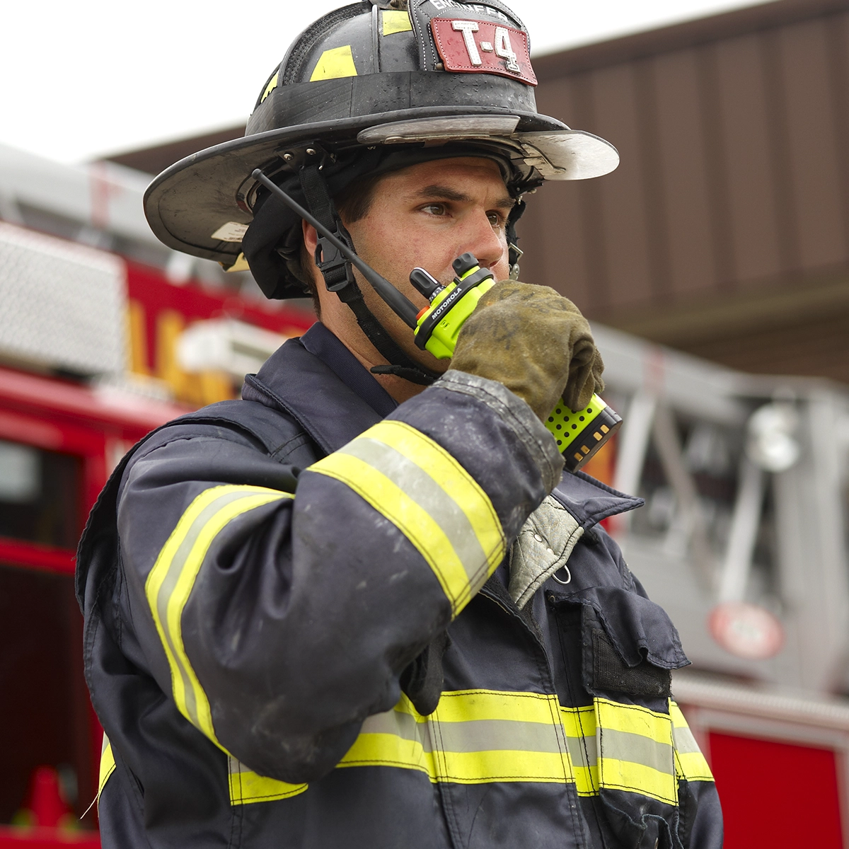 Firefighter in protective gear using a Motorola Solutions APX™ P25 two-way radio.