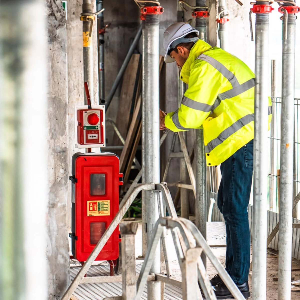 Red emergency communication unit mounted on scaffolding at a construction site, part of CSE Crosscom’s wireless safety solution