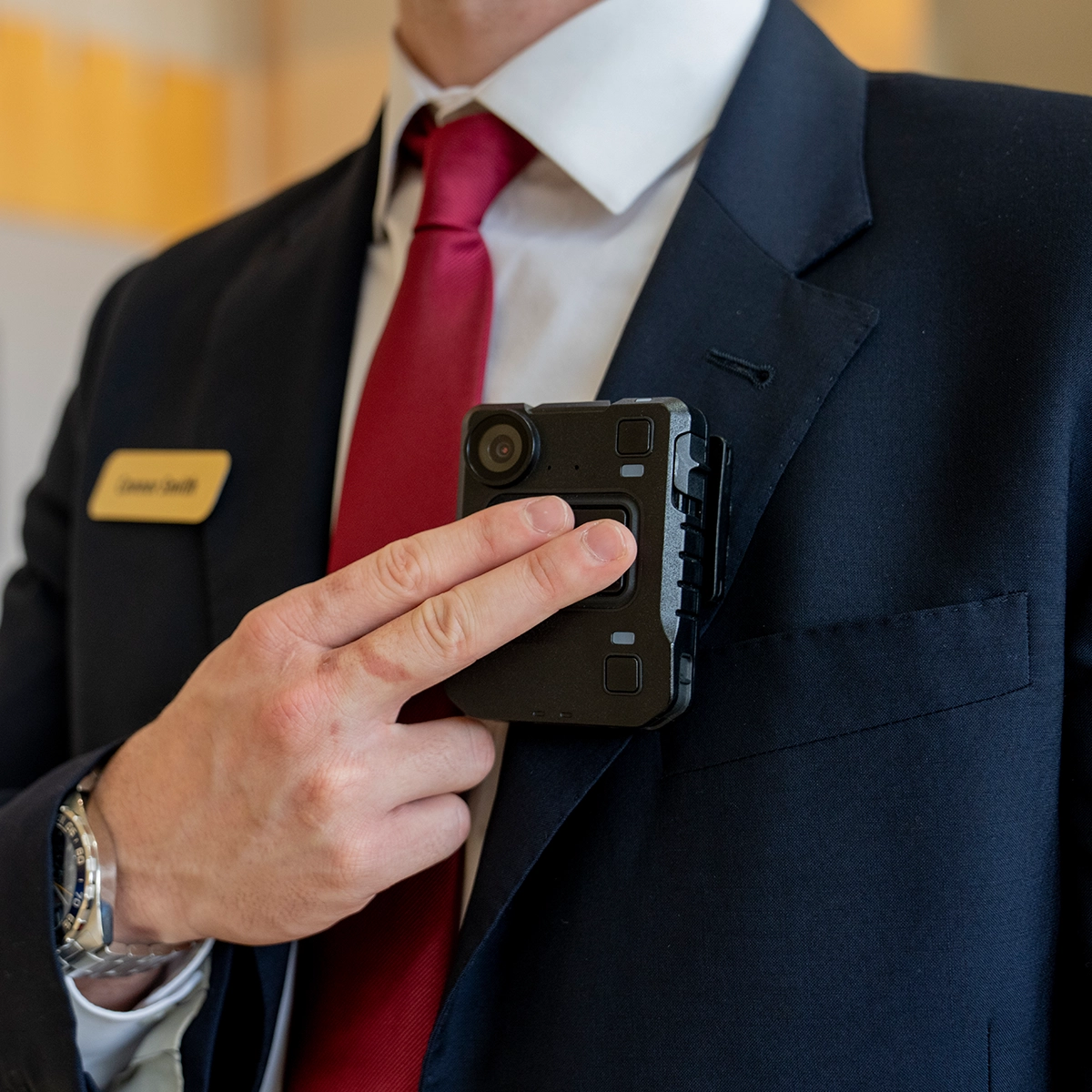 Motorola VB400 body-worn camera being fitted to a suit jacket, showcasing rugged design and incident recording capabilities