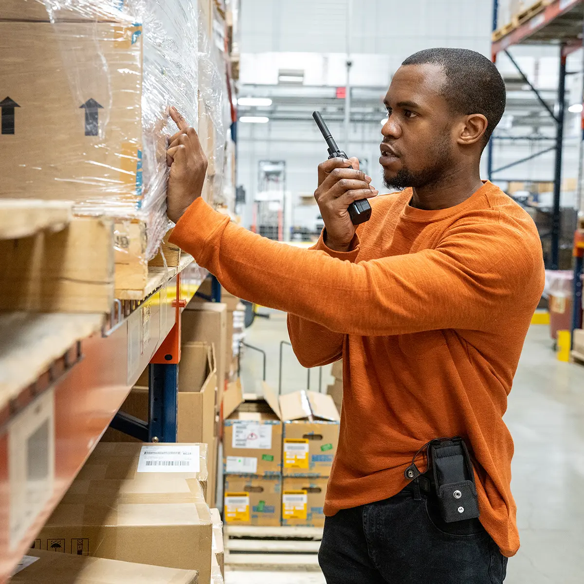 Person in a storage facility communicating via two-way radio, highlighting the role of signal boosters in improving connectivity.