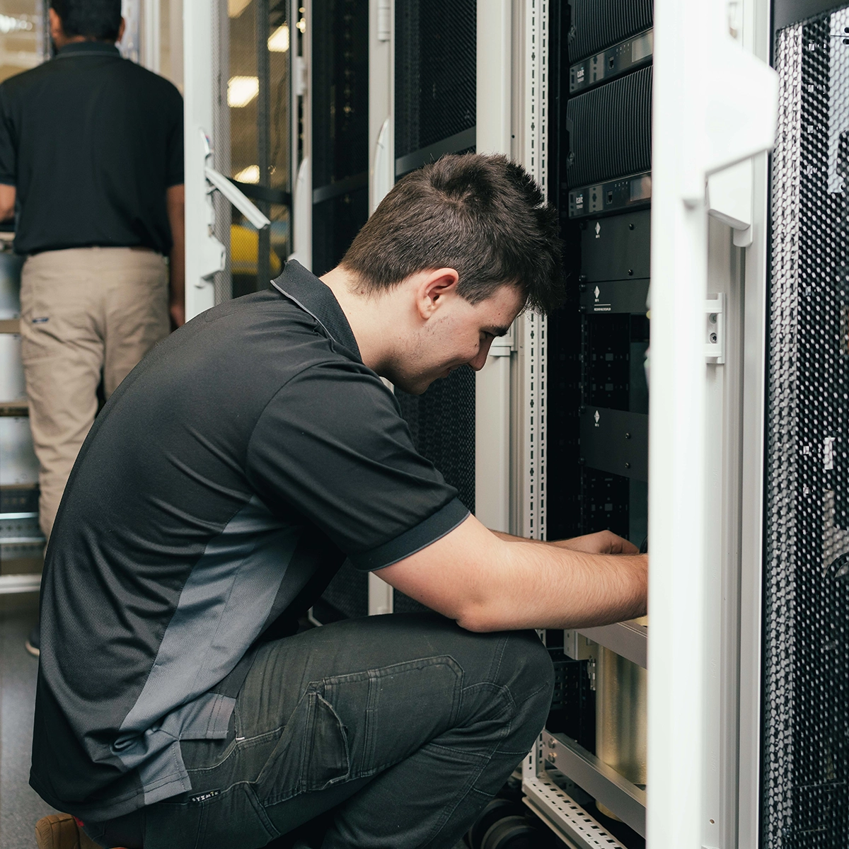A technician in a CSE Crosscom shirt working on server racks in a data centre.