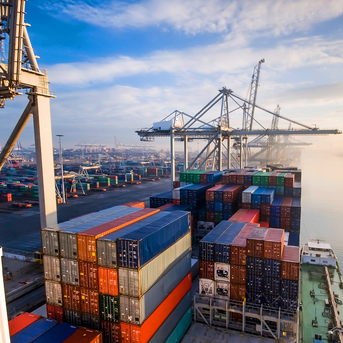 Shipping containers and cranes at a working port, illustrating IntelliPort’s role in enhancing visibility and control across port operations.