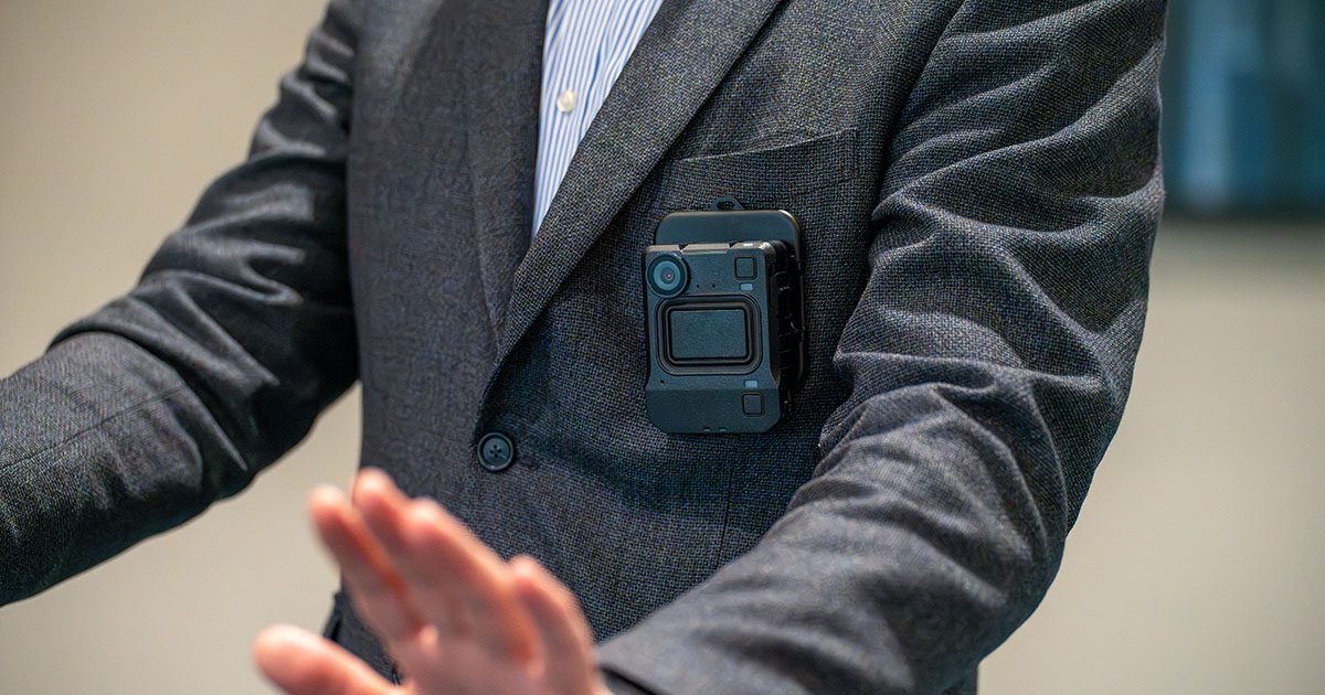 Lone security officer gestures at a person off camera while activating a body worn camera to capture rolling footage of the ongoing incident they're trying to deescalate. 