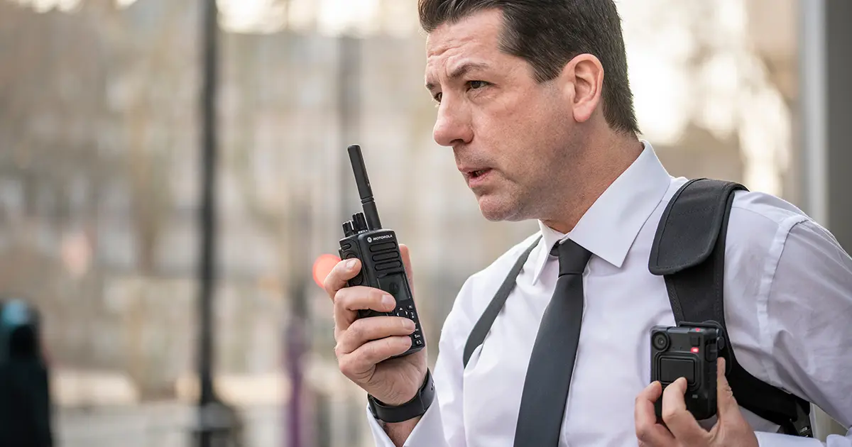 Security personnel using a Motorola two-way radio outdoors, representing reliable campus-wide communication in university environments.