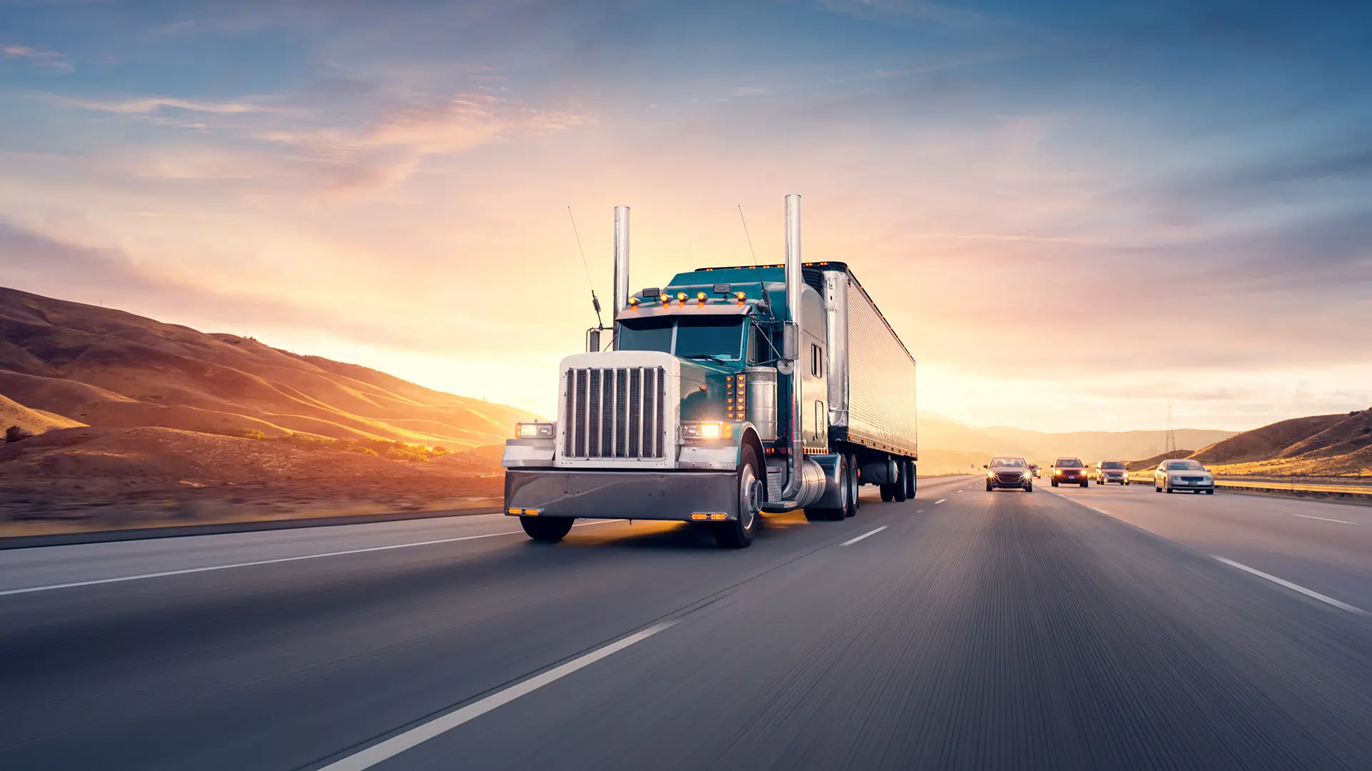 Truck on a major highway silhouetted by a sunset.