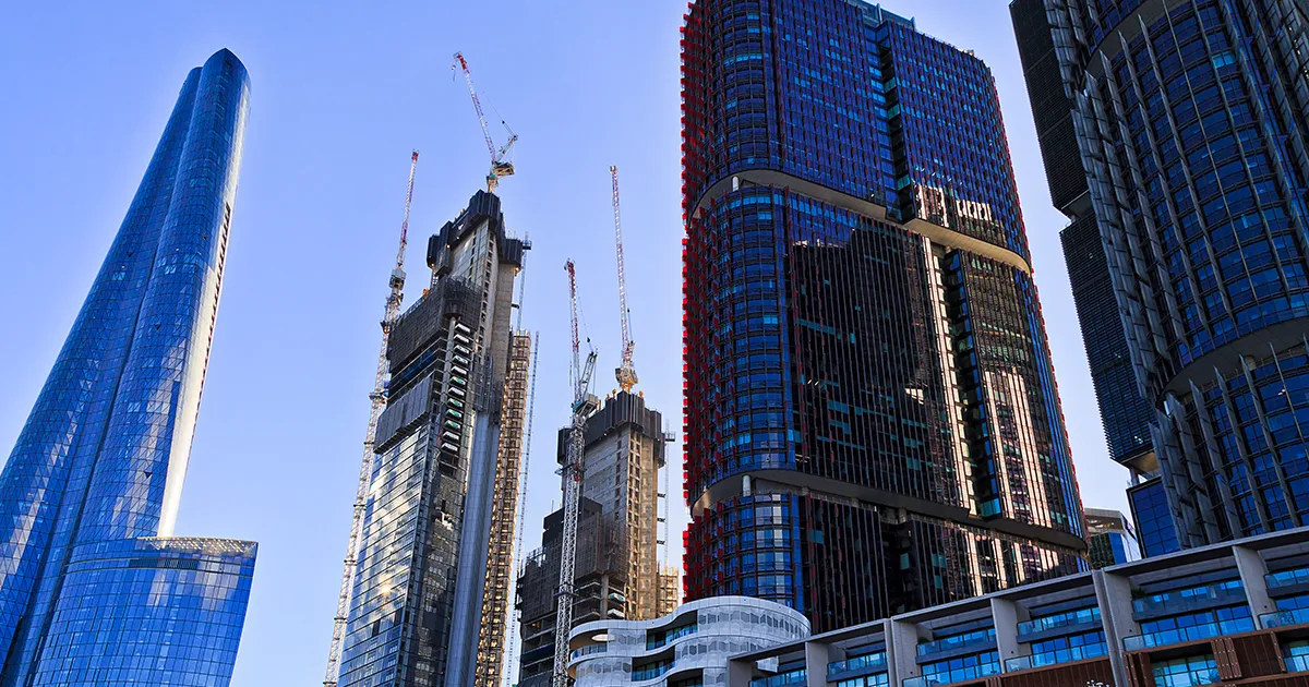 Several Tower Cranes are perched on a skycraper under construction in the Australia.