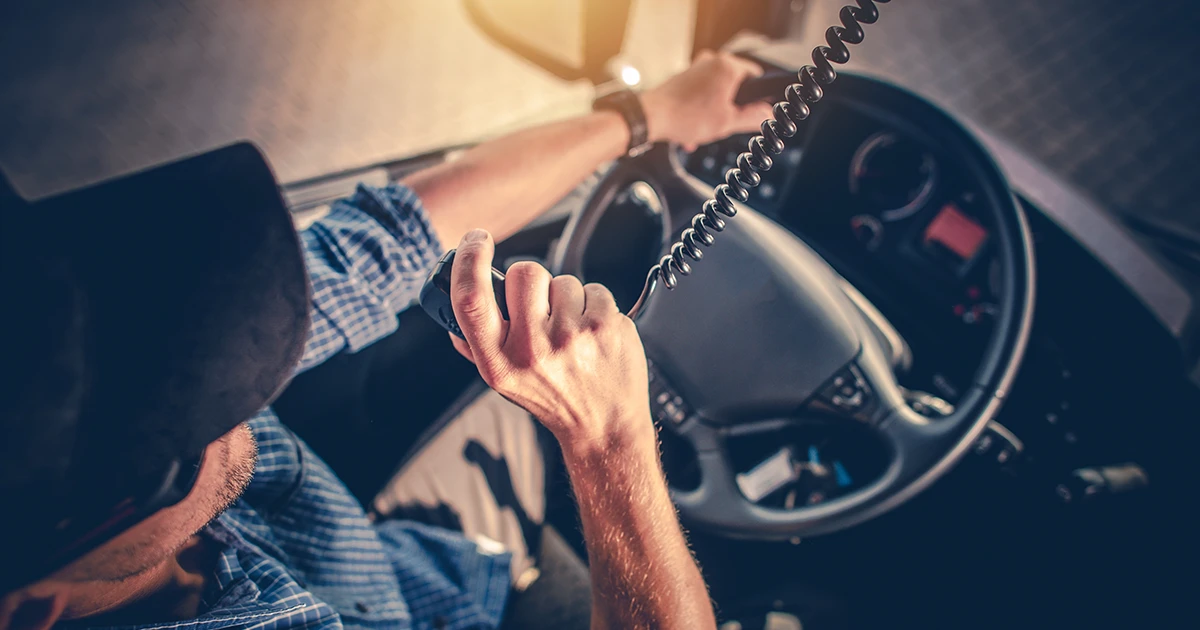 Australian truck driver uses their two-way radio handheld to communicate with the dispatch centre about road conditions.