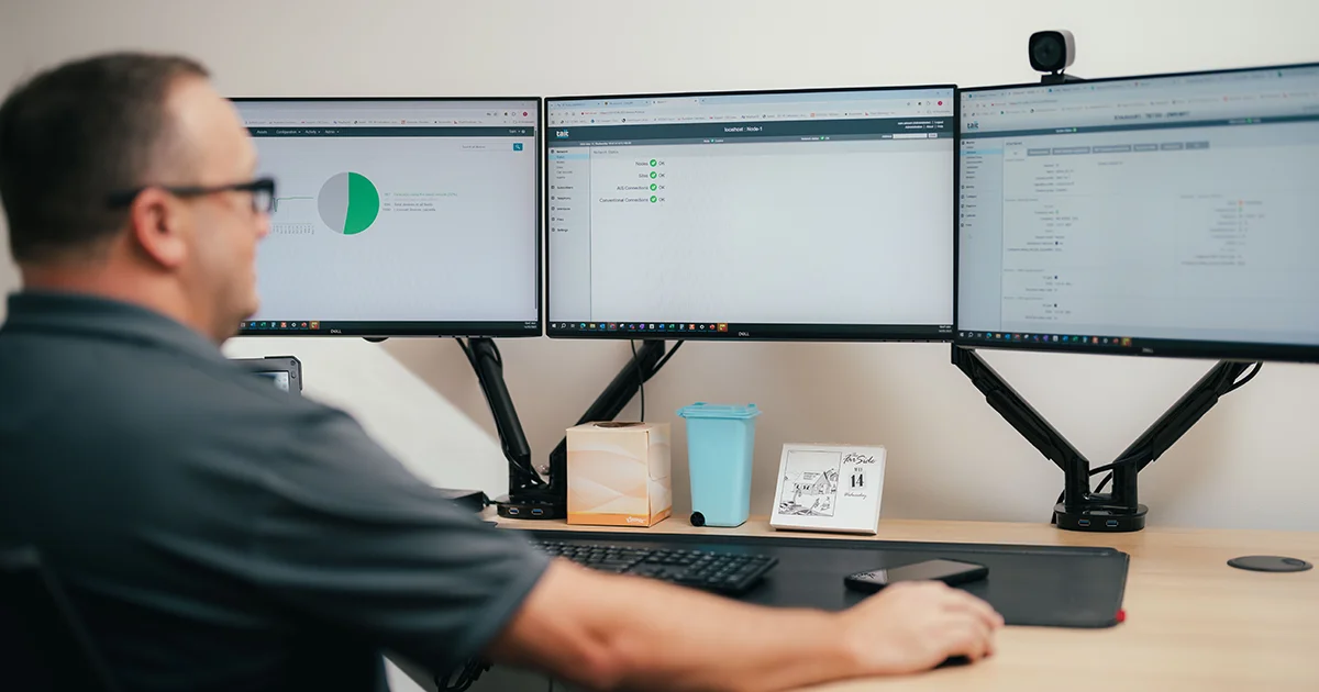 CSE Crosscom employee consults a row of monitors