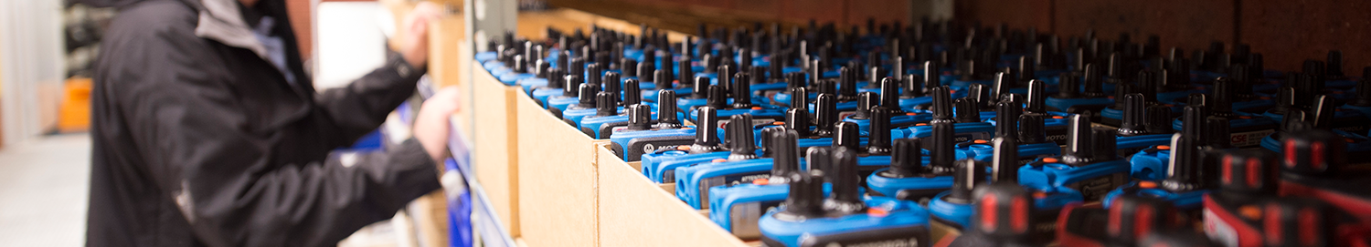 Row of rental two-way radios are stacked in a stock room.