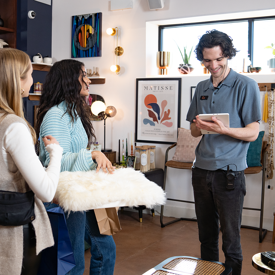 A retail worker chats to customers with a Motorola Solution's Curve two-way radio on their person, ready to communicate efficiently with other team members.